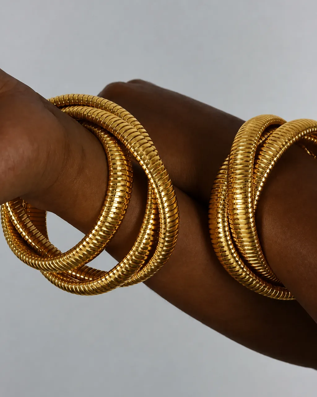 Stacked gold coil bangles worn on a wrist